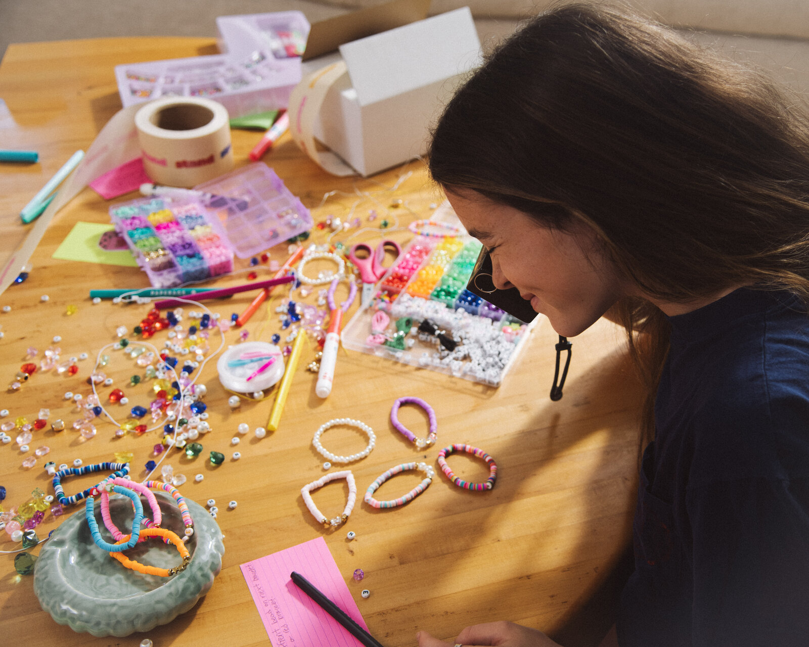 A girl photographing the beaded bracelets she just made, laid out on the table