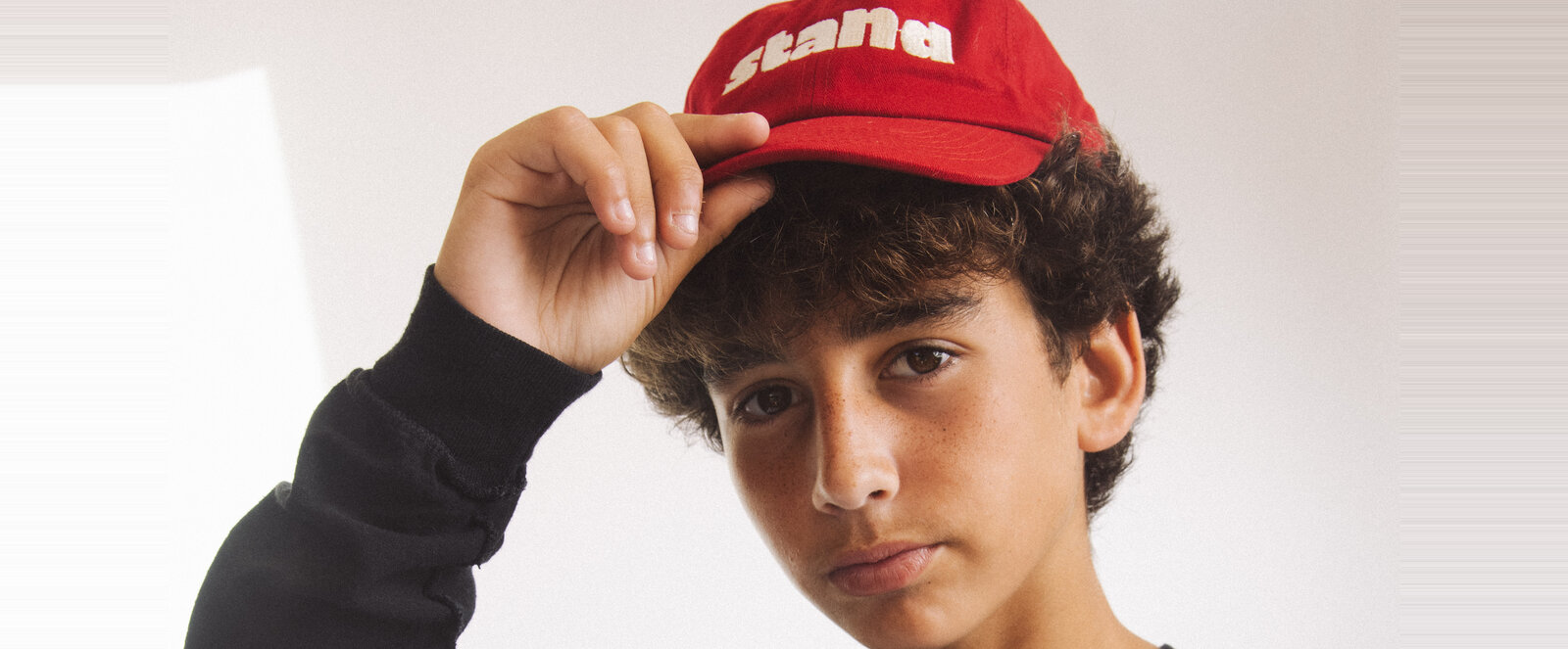 A kid in a red STAND cap tipping the brim
